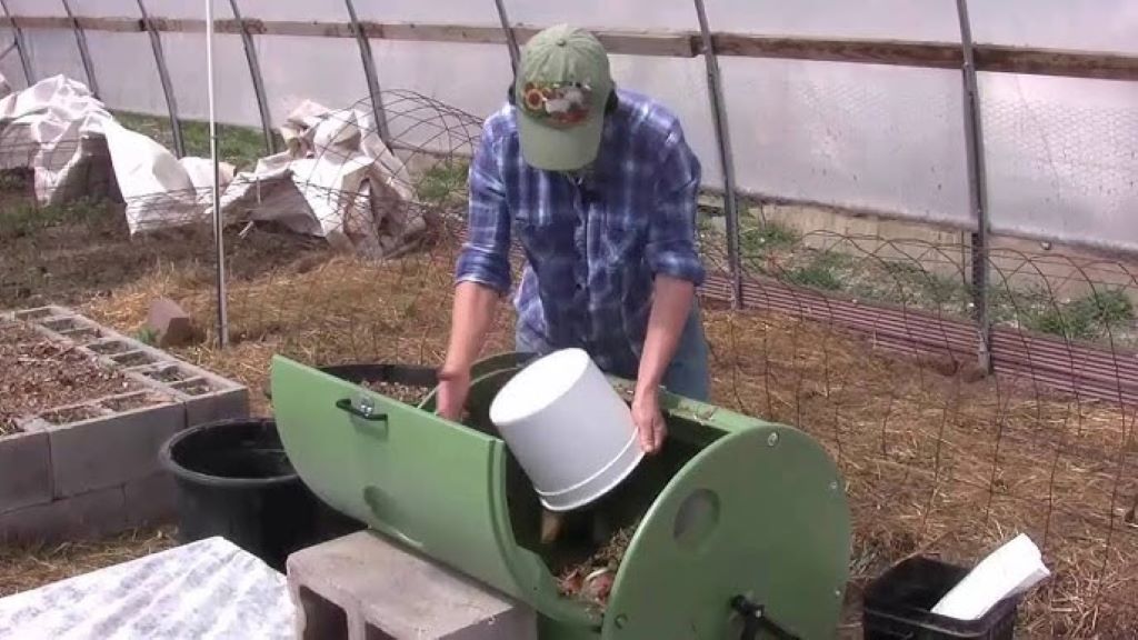 A person turning a compost tumbler in a garden, showing eco-friendly waste management for beginners learning how to start composting